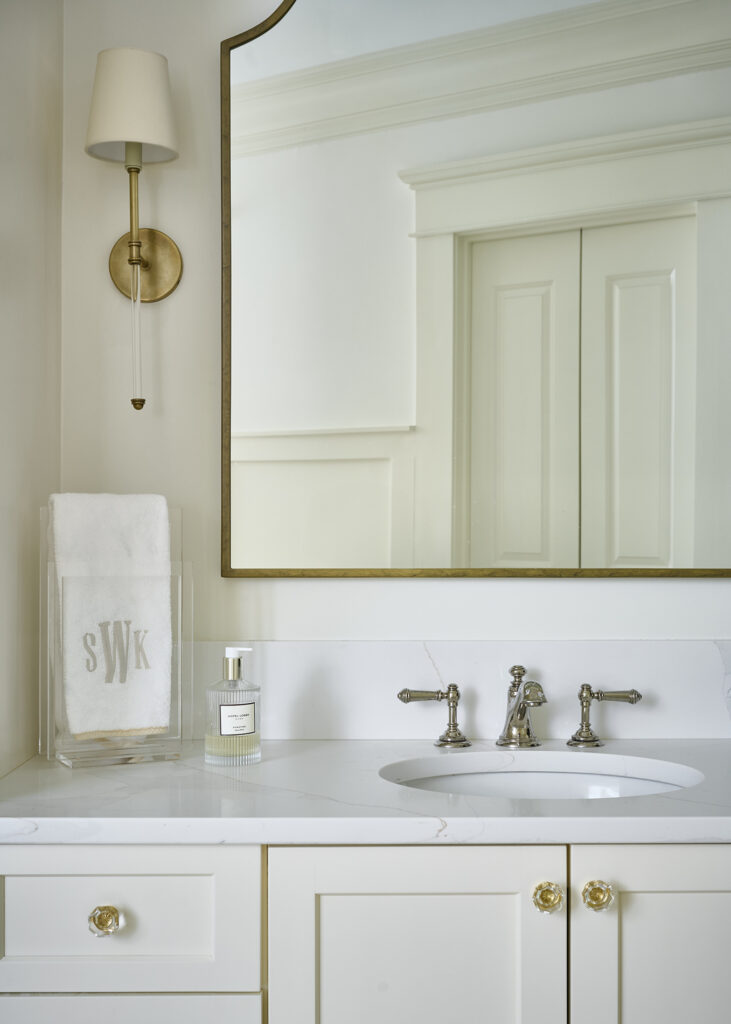 photo of classic coastal craftsman primary bathroom showing brass light fixtures, brass mirror, and brass hardware by an Atlanta Interior Designer in a Buckhead home.